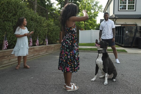 Dave Crenshaw watches his daughters practice commands with Doc, his service dog, in Kearny, N.J., on Monday, June 3, 2024. (AP Photo/Mary Conlon)