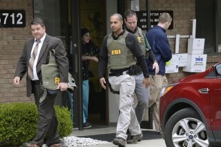 FILE - In this April 21, 2017 file photo, FBI agents leave the office of Dr. Fakhruddin Attar at the Burhani Clinic in Livonia, Mich., after completing a search for documents. A federal judge dismissed some charges Tuesday, Nov. 20, 2018, against eight people, including two doctors, in the genital mutilation of nine girls at the suburban Detroit clinic, finding it's up to states rather than Congress to regulate the practice. (Clarence Tabb Jr. /Detroit News via AP, File)
