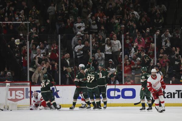 Minnesota Wild left wing Matt Boldy (12) celebrates with Kirill Kaprizov (97) and Joel Eriksson Ek (14) after scoring a goal during the second period of the team's NHL hockey game against the Detroit Red Wings on Monday, Feb. 14, 2022, in St. Paul, Minn. The goal marked Boldy's first hat trick in his NHL career. (AP Photo/Stacy Bengs)