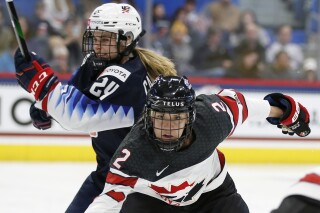 FILE - Canada's Meghan Agosta (2) defends against United States' Dani Cameranesi (24) during the first period of a rivalry series women's hockey game in Hartford, Conn., Saturday, Dec. 14, 2019. Agosta, who won three gold medals playing for Canada at the Olympics, is retiring from hockey. Agosta announced Friday, Feb. 16, 2024, that her playing career was over at age 37. (AP Photo/Michael Dwyer, File)