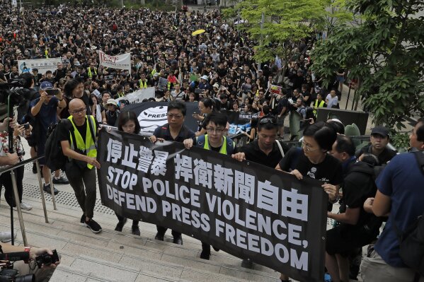 Hundreds of journalists hold banner with words "Stop police violence, defend press freedom" during a silent march to police headquarters and the government headquarters in Hong Kong, Sunday, July 14, 2019. They demand police to stop assaulting journalists and obstructing reporting. (AP Photo/Kin Cheung)