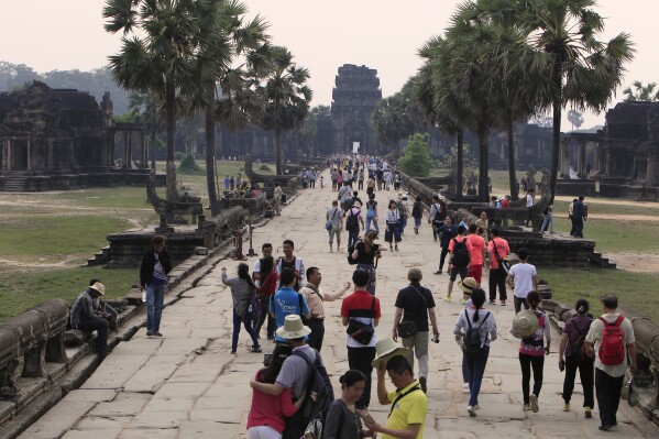 FILE - Tourists visit the Angkor Wat temple in Siem Reap, Cambodia, Wednesday, March 14, 2018. Commercial operations have begum at Cambodia’s newest and biggest airport, designed to serve as an upgraded gateway to the country’s major tourist attraction, the centuries-old Angkor Wat temple complex in the northwestern province of Siem Reap. (AP Photo/Heng Sinith, File)