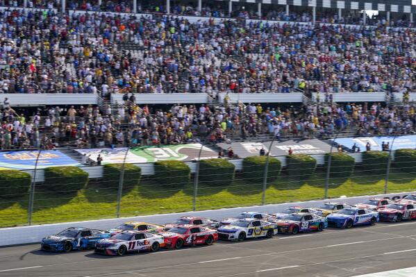 Ross Chastain (1) and Denny Hamlin (11) lead the pack past the grand stand on a restart late in the NASCAR Cup Series auto race at Pocono Raceway, Sunday, July 24, 2022, in Long Pond, Pa. (AP Photo/Matt Slocum)