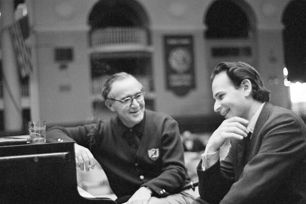 FILE - Bandleader Benny Goodman, left, and U.S. pianist Byron Janis talk during a pause in rehearsal for their joint concert in Leningrad, Russia, June 22, 1962. Both were on separate tours of the Soviet Union. Janis, a renowned American concert pianist and composer who broke barriers as a Cold War era culture ambassador and later overcame severe arthritis that nearly robbed him of his playing abilities, died at age 95. Janis passed away Thursday evening, March 14, 2024, at a hospital in New York City, according to his wife, Maria Cooper Janis. (AP Photo/George Syvertsen, File)