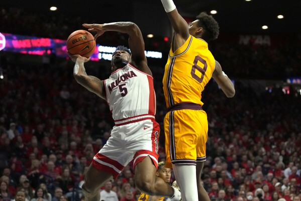 Arizona guard KJ Lewis (5) drives past Arizona State forward Alonzo Gaffney (8) during the first half of an NCAA college basketball game, Saturday, Feb. 17, 2024, in Tucson, Ariz. (AP Photo/Rick Scuteri)