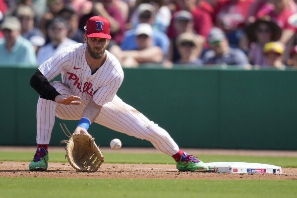 Philadelphia Phillies first baseman Bryce Harper fields the ball during the second inning of a spring training baseball game against the Atlanta Braves Wednesday, Feb. 28, 2024, in Clearwater, Fla. (AP Photo/Charlie Neibergall)