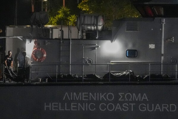 FILE - Rescue workers carry bodies from a coast guard vessel to a refrigerated truck at the port in Kalamata town, about 240 kilometers (150 miles) southwest of Athens, Greece on June 14, 2023. The international rights groups Amnesty International and Human Rights Watch allege on Thursday, Dec. 14, 2023, that Greek authorities have failed to properly investigate allegations by some survivors that the rescue mission had been mishandled. (AP Photo/Thanassis Stavrakis, File)