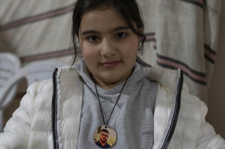 Rabea, 8, wears a pendant of her 17-year-old brother Tawfic Abdel Jabbar, a teenager from Louisiana who was fatally shot last week, at the family's Palestinian home village, Al-Mazra'a ash-Sharqiya, West Bank, Tuesday, Jan. 23, 2024. (AP Photo/Nasser Nasser)