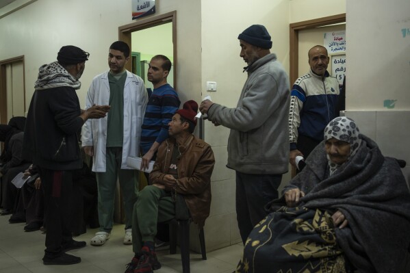 Dr. Suhaib Alhamss, the director of the Kuwaiti Hospital in Gaza's southern town of Rafah, speaks with patients during his work day outside the X-ray department of the hopsital, Thursday, Jan. 11, 2024. Overwhelmed with the dead and wounded as Rafah's population swells with displaced people, Alhamss has struggled to save lives as his hometown and hopsital have transformed over the 100 days of the Israel-Hamas war. (AP Photo/Fatima Shbair)