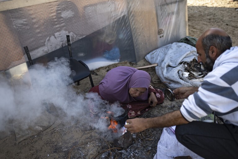 Des membres de la famille Abu Jarad, déplacés par le bombardement israélien de la bande de Gaza, préparent du thé dans un camp de tentes de fortune dans la région de Muwasi, au sud de Gaza, le lundi 1er janvier 2024. (AP Photo/Fatima Shbair)