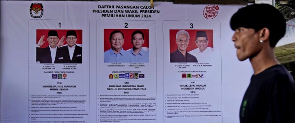 A man walks past a General Election Commission's banner showing the photos of presidential candidates, from left, former Jakarta Governor Anies Baswedan and his running mate Muhaimin Iskandar, former special forces general Prabowo Subianto and his running mate Gibran Rakabuming Raka, the eldest son of Indonesian President Joko Widodo, and former Central Java Governor Ganjar Pranowo and his running mate Mahfud MD in Jakarta, Indonesia, Monday, Jan. 22, 2024. (AP Photo/Dita Alangkara)