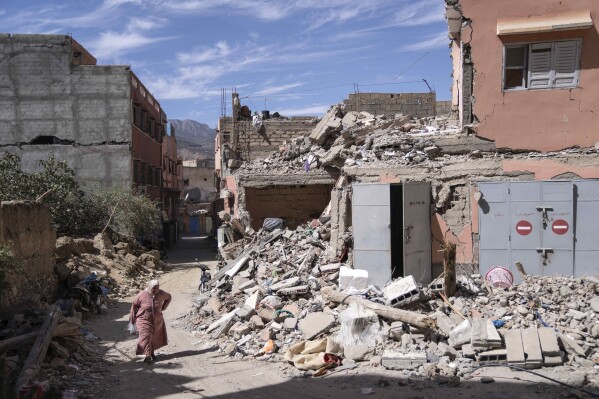 A woman walks past rubble that was caused the September earthquake in Amizmiz, outside Marrakech, Morocco, Friday, Oct. 6, 2023. Morocco has pledged to rebuild from a September earthquake in line with its architectural heritage. Villagers and architects agree that earthquake-safe construction is a top priority. That’s created a push for modern building materials. But the government says it wants to rebuild in line with Morocco’s cultural and architectural heritage. (AP Photo/Mosa'ab Elshamy)