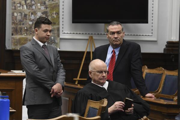 Kyle Rittenhouse and defense attorney Mark Richards stand as Judge Bruce Schroeder makes a personal call during Rittenhouse's trial at the Kenosha County Courthouse in Kenosha, Wis., on Friday, Nov. 12, 2021. Rittenhouse is accused of killing two people and wounding a third during a protest over police brutality in Kenosha, last year. (Mark Hertzberg /Pool Photo via AP)