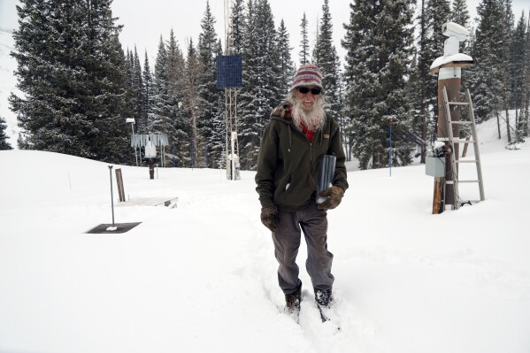 Billy Barr holds his canister with newly fallen snow Wednesday, March 13, 2024, in Gothic, Colo. So-called “citizen scientists” like Barr have long played important roles in gathering data to help researchers better understand the environment. His once hand-recorded measurements have informed numerous scientific papers and helped calibrate aerial snow sensing tools. (ĢӰԺ Photo/Brittany Peterson)