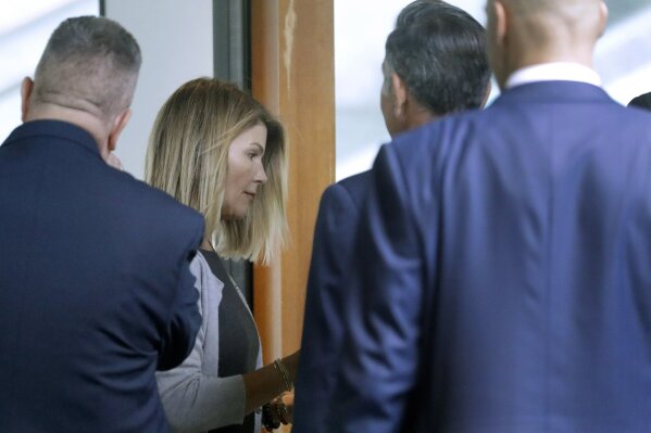 Lori Loughlin, second from left, and her husband Mossimo Giannulli, second from right, enter the back door at federal court Tuesday, Aug. 27, 2019, in Boston, for a hearing in a nationwide college admissions bribery scandal. (AP Photo/Steven Senne)