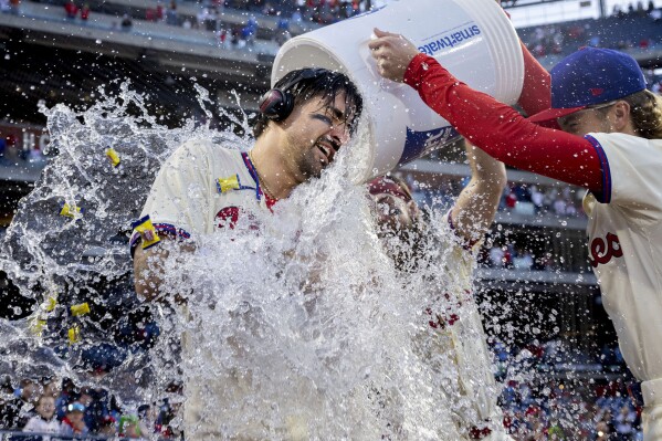 Philadelphia Phillies' Nick Castellanos, left, is doused by teammates Bryson Stott, right, Brandon Marsh, center, after hitting a walkoff single in the ninth inning of a baseball game against the Pittsburgh Pirates, Saturday, April 13, 2024, in Philadelphia. (AP Photo/Laurence Kesterson)
