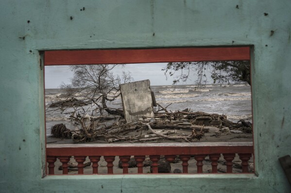 A window frames a portion of the shoreline littered with debris left from flooding driven by a Gulf of Mexico sea-level rise, in the coastal community of El Bosque, Mexico, Wednesday, Nov. 29, 2023. (AP Photo/Felix Marquez)