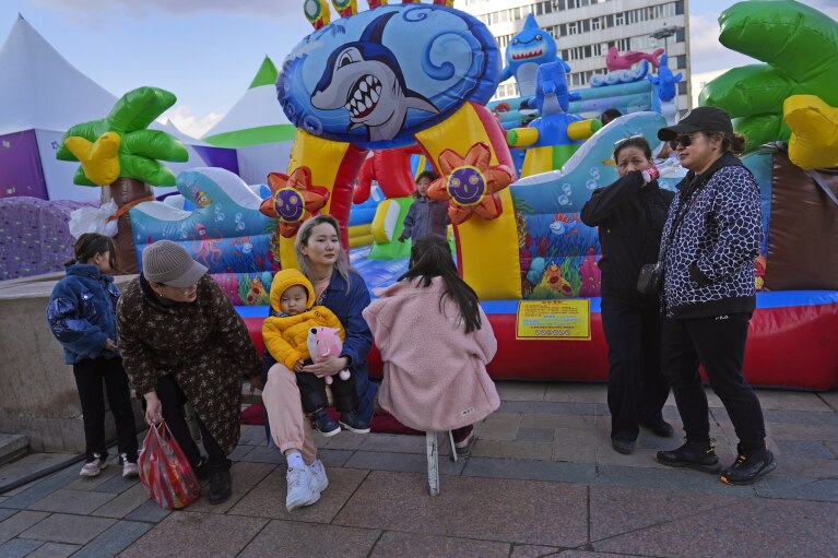 Women wait as their children play during a fair in Ulaanbaatar, the capital of Mongolia, Sunday, May 21, 2023. Mongolia, a nation bordered by China and Russia, is known for vast, rugged expanses and nomadic culture. (AP Photo/Manish Swarup)