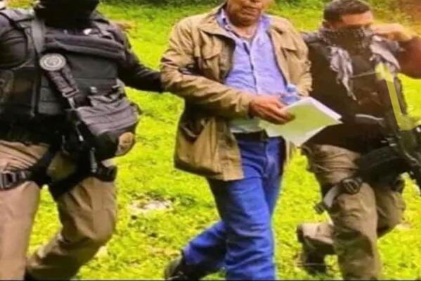 In this government handout photo provided by Mexico's Secretariat of the Navy, agents escort drug trafficker Rafael Caro Quintero, in Sinaloa state, Mexico, Friday, July 15, 2022, captured deep in the mountains of his home state. It was a 6-year-old bloodhound named “Max” who rousted Caro Quintero from the undergrowth. (Mexico's Secretariat of the Navy via AP)