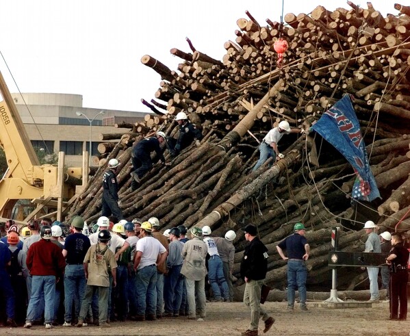 FILE - Texas A&M students and rescue workers gathered at the base of the collapsed bonfire stack as the search continues for victims in College Station, Texas, Nov. 18, 1999. (AP Photo/Pat Sullivan, File)