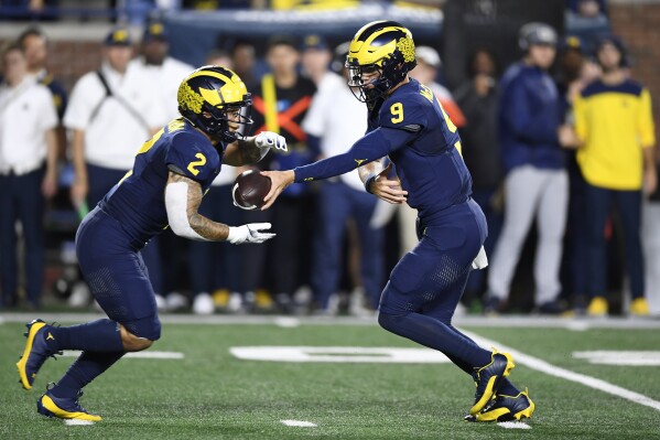 Michigan quarterback J.J. McCarthy, right, hands the ball to running back Blake Corum (2) in the first quarter of an NCAA college football game against Bowling Green, Saturday, Sept. 16, 2023, in Ann Arbor, Mich. (AP Photo/Jose Juarez)