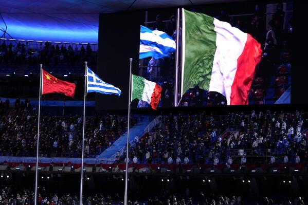 The Italian flag, right, flies next to Greece, center, and China during the closing ceremony of the 2022 Winter Olympics, Sunday, Feb. 20, 2022, in Beijing. (AP Photo/Bernat Armangue)