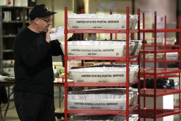 FILE - An Allegheny County worker processes mail-in and absentee ballots in Pittsburgh, April 18, 2024. At rallies and in social media posts, former President Donald Trump has been trying to assure Republican voters that casting ballots by mail and other forms of early voting are “all good options.” (AP Photo/Gene J. Puskar, File)