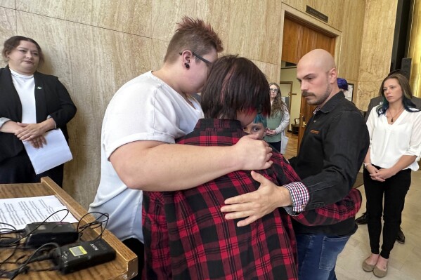 FILE - Tate Dolney, a 12-year-old transgender boy from Fargo, N.D., is embraced by his parents, Devon and Robert Dolney, after a news conference, Sept. 14, 2023, at the state Capitol in Bismarck, N.D. A North Dakota judge on Wednesday, June 5, 2024, denied a request for a preliminary injunction to block the state's law banning gender-affirming care for children. The Dolneys are plaintiffs in the lawsuit seeking to overturn the 2023 law as unconstitutional. (AP Photo/Jack Dura, File)