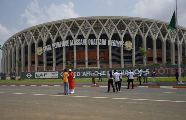 People stand in front of Stade Olympique Alassane Ouattara B'Ebimpe before the African Cup of Nations Group A soccer match between Nigeria and Equatorial Guinea's in Abidjan, Ivory Coast, Sunday, Jan. 14, 2024. (AP Photo/Sunday Alamba)
