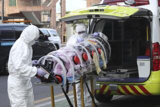 Medial workers carry a patient infected with the coronavirus onto an ambulance at an elderly care facility in Ulsan, South Korea, Monday, Dec. 7, 2020. South Korea's health minister said Monday that the Seoul metropolitan area is now a "COVID-19 war zone," as the country reported another 615 new infections and the virus appeared to be spreading faster. (Kim Young-tae/Yonhap via AP)