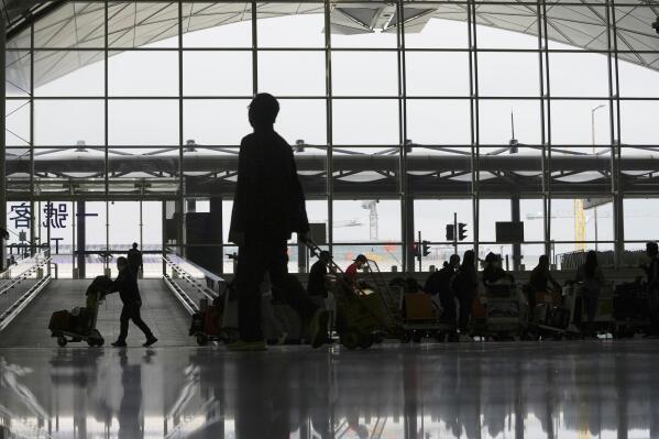 Travelers walk at the Hong Kong airport, Friday, Feb. 18, 2022. (AP Photo/Kin Cheung)