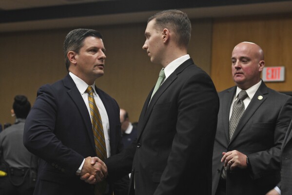 State Trooper Brian North, right, shakes hands with his defense attorney, Frank Riccio, after a jury delivered a verdict of not guilty on all counts in Connecticut Superior Court in Milford, Conn., Friday, March 15, 2024. North was acquitted of all charges Friday in the death of Mubarak Soulemane, a community college student with mental illness who was shot as he sat behind the wheel of a stolen car holding a kitchen knife. (Ned Gerard/Hearst Connecticut Media/Pool)