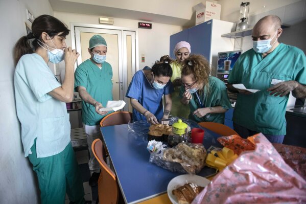 In this photo taken on Friday, April 10, 2020 nurse Cristina Settembrese, center, shares food and Easter eggs with colleagues at the San Paolo hospital before starting her work shift in Milan, Italy. (AP Photo/Luca Bruno)