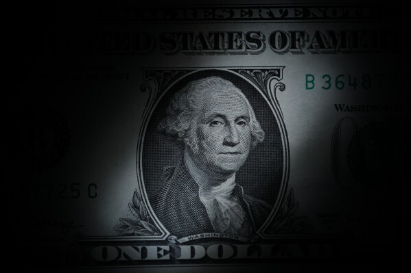 FILE - The likeness of George Washington is seen on a U.S. one dollar bill, March 13, 2023, in Marple Township, Pa. The Congressional Budget Office said Friday, Dec. 15, that it expects inflation to nearly hit the Federal Reserve's 2% target rate in 2024, as overall growth is expected to slow and unemployment is expected to rise into 2025, according to updated economic projections for the next two years. (AP Photo/Matt Slocum, File)