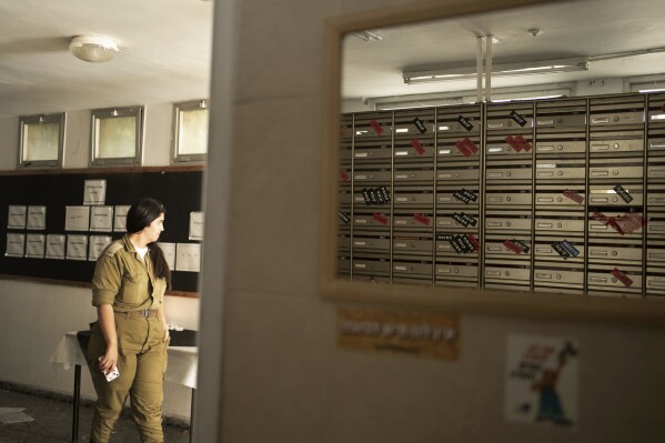 A soldier walks through the mailroom in Kibbutz Nir Oz, where mailboxes are labeled with the status if it's residents - killed, captured, or recovered - near the Israel-Gaza border on Nov. 21, 2023. An Associated Press review of Hamas instruction manuals shows the group planned ahead of time to target civilians. (AP Photo/Maya Alleruzzo)
