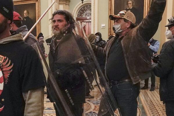 FILE - Rioters, including Dominic Pezzola, center with police shield, are confronted by U.S. Capitol Police officers outside the Senate Chamber inside the Capitol, Wednesday, Jan. 6, 2021, in Washington. A Proud Boy far-right extremist group member whose smashing out of a window at the U.S. Capitol on Jan. 6, 2021, allowed some of the first rioters to enter the building testified Wednesday, April 19, 2023, that he acted alone. Pezzola is one of five Proud Boys facing seditious conspiracy and other charges in one of the most high-profile trials to emerge from the insurrection. (AP Photo/Manuel Balce Ceneta, File)