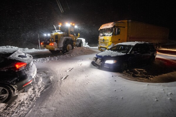 CORRECTS YEAR TO 2024 Snow is cleared with wheel loaders as cars and trucks are recovered and people are evacuated with the Home Guard's tracked vehicle at Ekeröd on the E22 between Hörby and Kristianstad in southern Sweden, Thursday, Jan. 4, 2024. Up to 300 cars stuck in a queue due to large amounts of snow that fell on the roadway and limited access, according to the police. (Johan Nilsson/TT News Agency via AP)