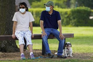 Jeff and Raynette Ho wear face masks as they sit with their dog at Custer Park on Thursday, July 2, 2020, in Richardson, Texas. Gov. Greg Abbott on Thursday ordered Texans in most of the state to wear face masks in public beginning Friday at noon as cases of the coronavirus surge. (Smiley N. Pool/The Dallas Morning News via AP)