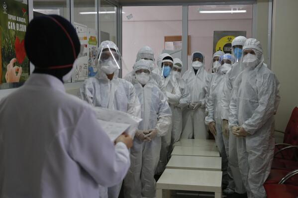 In this Friday, May 15, 2020 photo, Dr. Melek Nur Aslan, left, the local health director for Fatih, a large district in the historic peninsula of Istanbul briefs a team of contact tracers with Turkey's Health Ministry's coronavirus contact tracing team, clad in white protective gear, masks and face shields. Teams of contact tracers in Istanbul, the epicenter of the pandemic in Turkey and its most populous city, and also nationwide, are going house to house to test people experiencing COVID-19 symptoms and inform patients on isolation.  (AP Photo/Emrah Gurel)