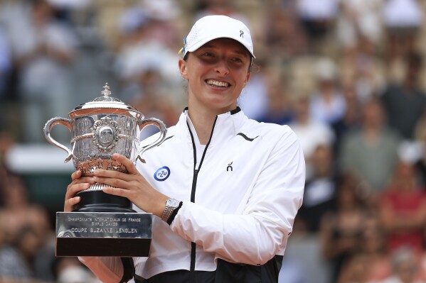 FILE - Poland's Iga Swiatek holds the trophy as she celebrates winning the women's final match of the French Open tennis tournament against Karolina Muchova of the Czech Republic in three sets, 6-2, 5-7, 6-4, at the Roland Garros stadium in Paris, Saturday, June 10, 2023. Swiatek has won two titles in a row, and three overall, at the French Open, which starts Sunday at Roland Garros in Paris. (AP Photo/Aurelien Morissard, File)