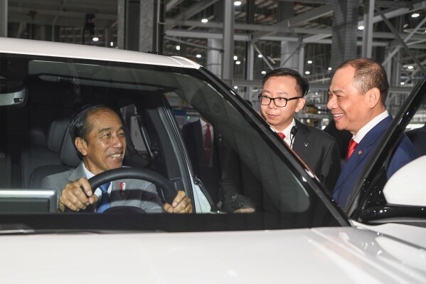 In this photo released by VinFast, Indonesian President Joko Widodo sits behind the wheel of a VinFast electric car as Vingroup Chairman and VinFast Global CEO Pham Nhat Vuong, right, looks on in Hai Phong, Vietnam on Saturday, Jan. 13, 2024. (VinFast via AP)