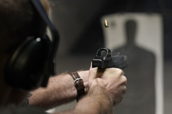 FILE - A man fires his pistol at an indoor shooting range during a qualification course to renew his Carry Concealed handgun permit at the Placer Sporting Club, July 1, 2022, in Roseville, Calif. A federal judge on Wednesday, Dec. 20, 2023, temporarily blocked a California law that would have banned carrying firearms in most public places, ruling that it violates the Second Amendment of the U.S. Constitution and deprives people of their ability to defend themselves and their loved ones. (AP Photo/Rich Pedroncelli, File)