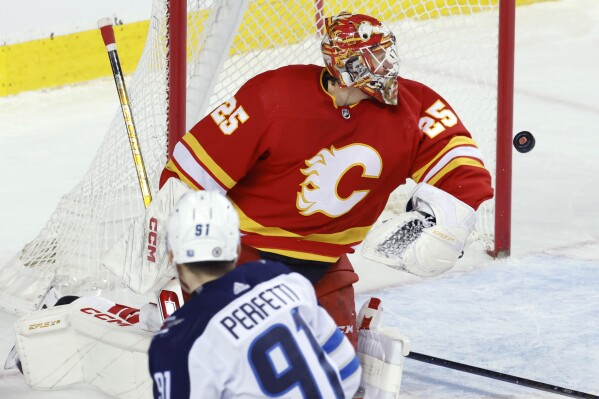Calgary Flames goalie Jacob Markstrom stops a shot by Winnipeg Jets' Cole Perfetti during the second period of an NHL hockey game in Calgary, Alberta, Monday, Feb. 19, 2024. (Larry MacDougal/The Canadian Press via AP)
