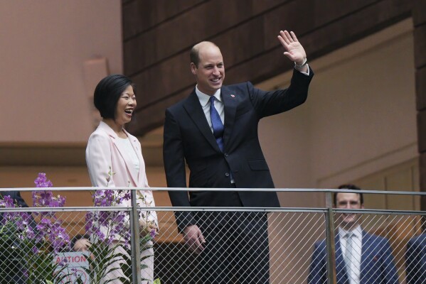 Britain's Prince William, right, waves as with Sim Ann, Senior Minister of State for Foreign Affairs of Singapore, he arrives at Jewel Changi airport, Singapore, Sunday, Nov. 5, 2023. (AP Photo/Vincent Thian)