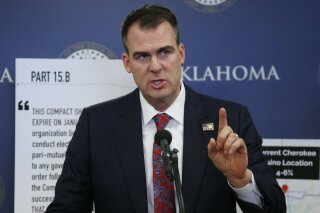 FILE - In this Dec. 17, 2019, file photo, Oklahoma Gov. Kevin Stitt gestures during a news conference in Oklahoma City. Stitt on Thursday, Jan.23, 2020, banned state-funded travel to the state of California, saying it's in response to similar bans California has put in place on travel to the Sooner State. The first-term Republican issued an executive order that prohibits all non-essential travel by state employees to California, with exceptions for business recruiting trips, college sports games and trips by schools to participate in programs.(AP Photo/Sue Ogrocki, File)