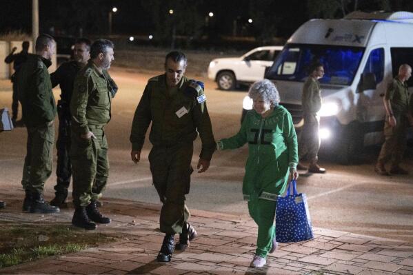 Ruth Munder, a released Israeli hostage, walks with an Israeli soldier shortly after her arrival in Israel on Friday, Nov. 24, 2023. A four-day cease-fire in the Israel-Hamas war began in Gaza on Friday with an exchange of hostages and prisoners. (IDF via AP)