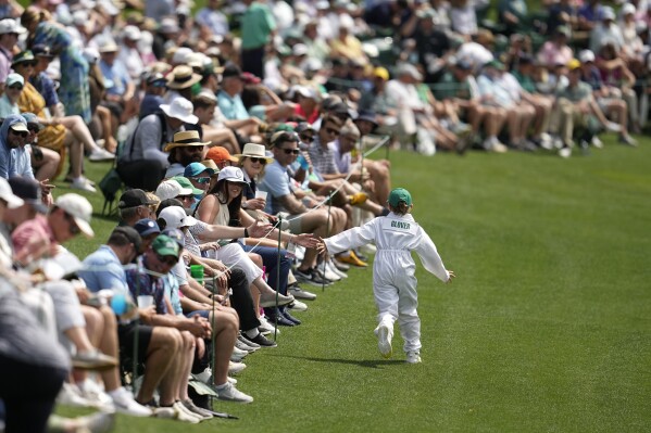 Lucas Glover's son, Lucas Jr. greets fans on the fifth hole during the par-3 contest at the Masters golf tournament at Augusta National Golf Club Wednesday, April 10, 2024, in Augusta, GA. (AP Photo/George Walker IV)