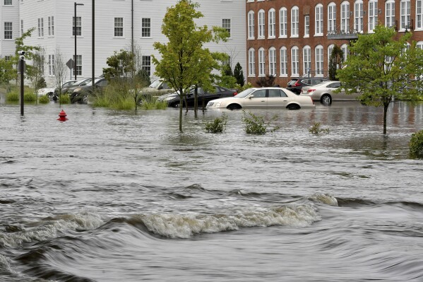 Water from a nearby overflowing river submerges the parking lot at the Sterling Lofts apartment complex in Attleboro, Mass. Tuesday, Sept. 12, 2023. (Mark Stockwell/The Sun Chronicle via AP)