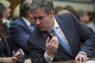 Michael Cohen, President Donald Trump's former lawyer, reacts after speaking with his lawyer Lanny Davis of Washington, as he testifies before the House Oversight and Reform Committee, on Capitol Hill, Wednesday, Feb. 27, 2019, in Washington. (AP Photo/Alex Brandon)