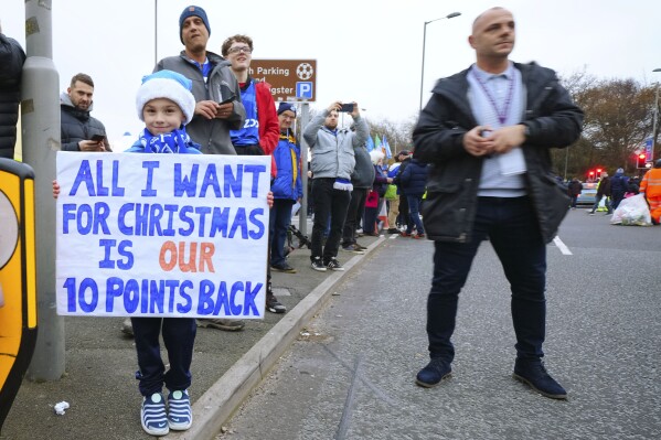 A child holds a placard reading 'All I want for Christmas is our ten points back' prior to the start of the English Premier League soccer match between Everton and Manchester United, at Goodison Park Stadium, in Liverpool, England, Sunday , Nov. 26, 2023. (AP Photo/Jon Super)